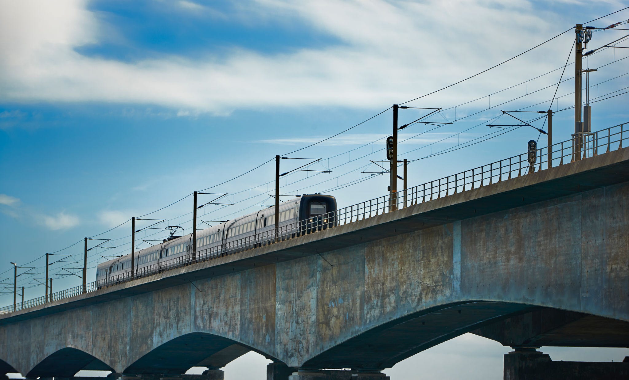 Train crossing a bridge looking small at the heavy construction.