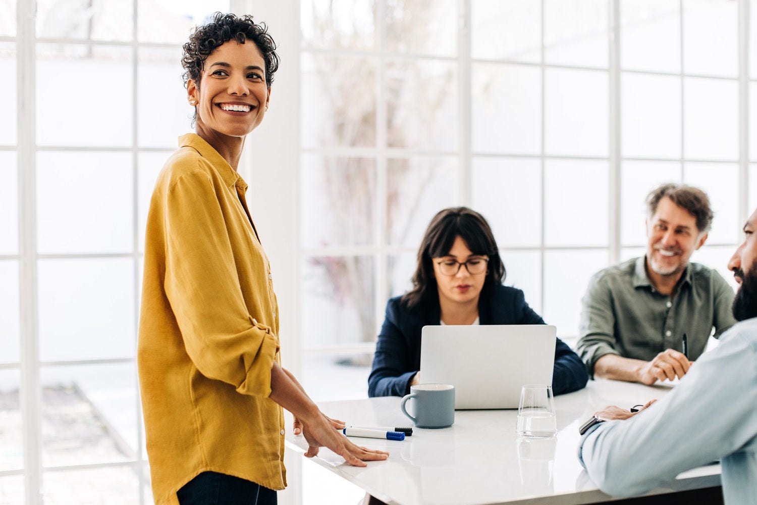 Black business woman having a meeting with her colleagues in a boardroom. Happy business woman leading a discussion in an office. Female project manager standing in front of her team.