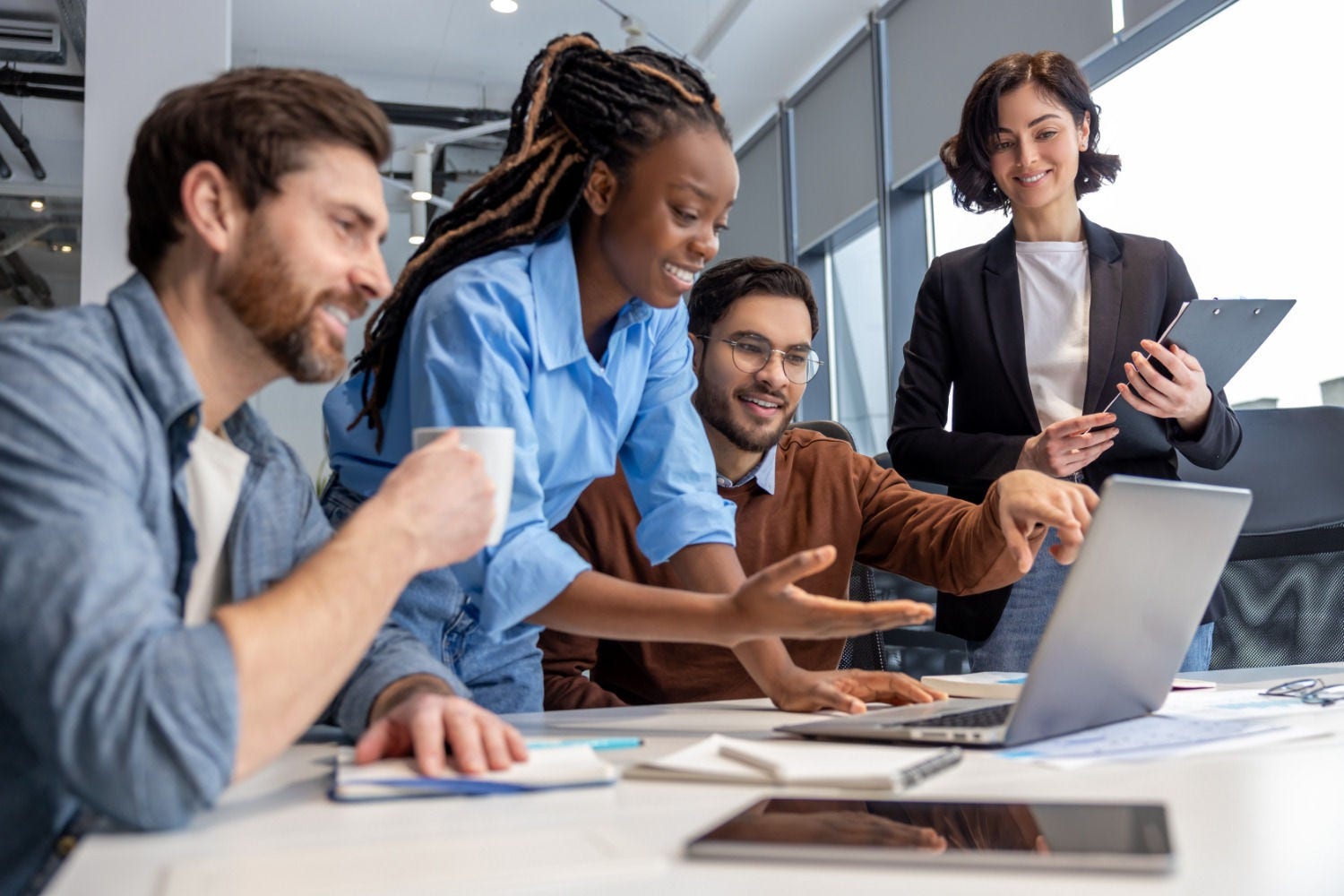 People smiling whilst looking at a laptop on an office table